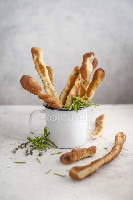 Bâtonnets de pain aux herbes dans une tasse en émail — Photo de stock
