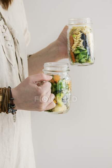 A woman in a linen dress holding two salad jars — Stock Photo