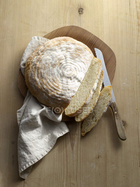 A loaf of potato bread, sliced on a wooden surface — Stock Photo