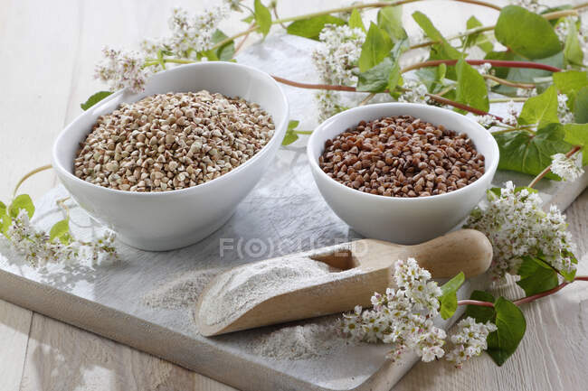 Roasted and unroasted buckwheat groats with buckwheat flowers — Stock Photo