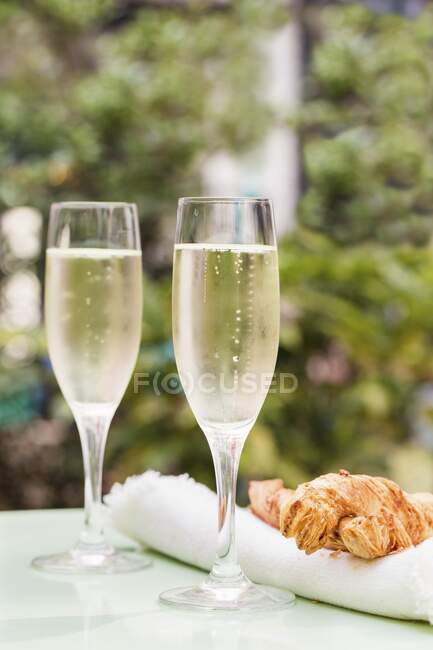 Two glasses of Prosecco on a table outside with large cheese straws — Stock Photo