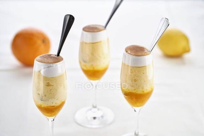 Orange and lemon cream desserts in glasses with spoons — Stock Photo