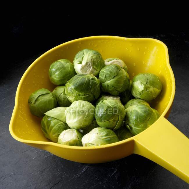 Brussels sprouts in yellow colander — Stock Photo