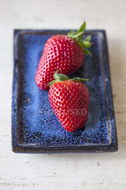Deux fraises sur une assiette bleue — Photo de stock