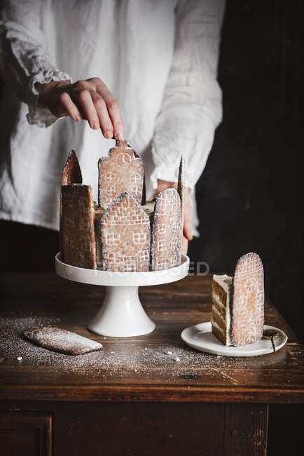Manos de mujer sosteniendo un delicioso pastel con un cuchillo en una mesa de madera - foto de stock