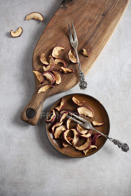 Fette di mela secche su un piatto e una tavola di legno — Foto stock