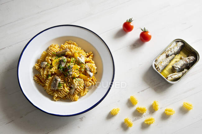Pasta with sardines and tomatoes on white table surface — Stock Photo