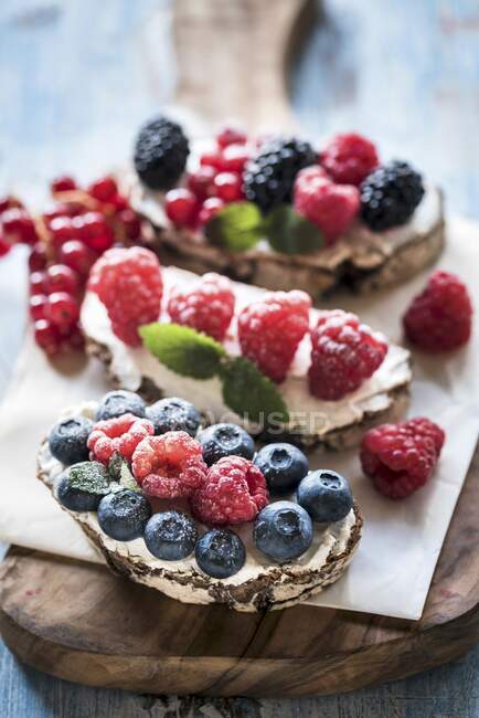 Berries and cream cheese bruschettas on wooden board — Stock Photo