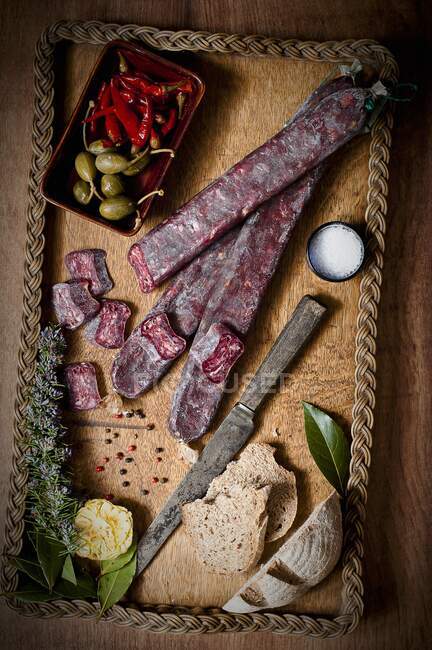 Salame de carne cortada em uma bandeja de madeira com pão e sal — Fotografia de Stock