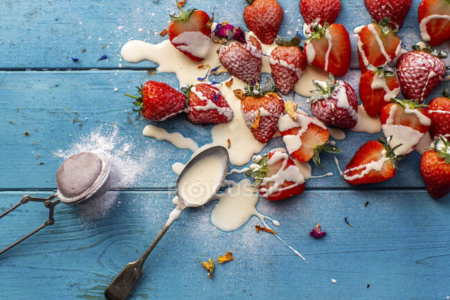 Strawberries and cream topped with icing sugar and edible petals — Stock Photo
