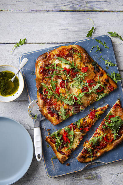 Pizza fatta in casa con salame, mozzarella, peperoni dolci, rucola e olio di basilico all'aglio — Foto stock