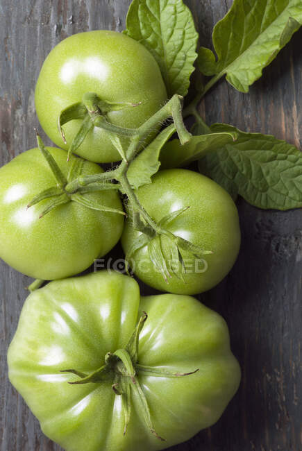 Green and red tomatoes on a wooden background — Stock Photo