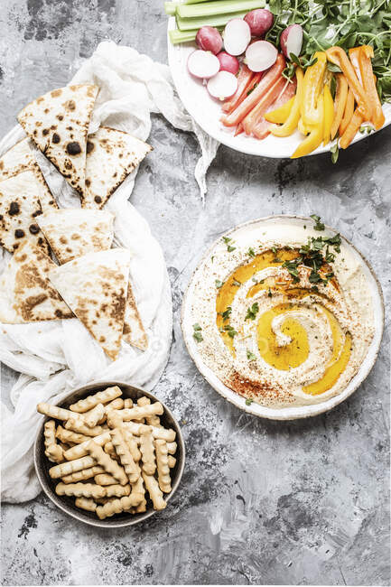 Hummus served with vegetables and pastries, top view — Stock Photo
