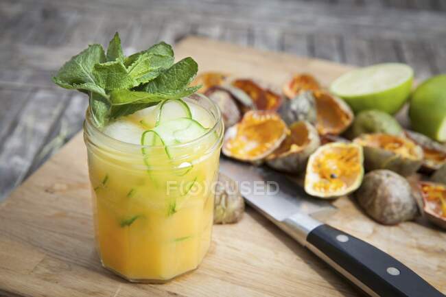 Passionfruit cocktail with mint and lime on wooden board — Stock Photo