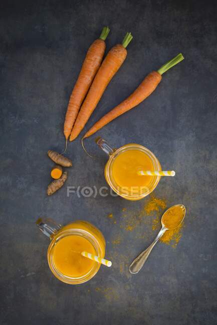 Морковь и куркума в стаканах с соломинками (см. сверху)) — стоковое фото