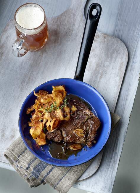 Meat with potato chips and glass of dark beer — Stock Photo