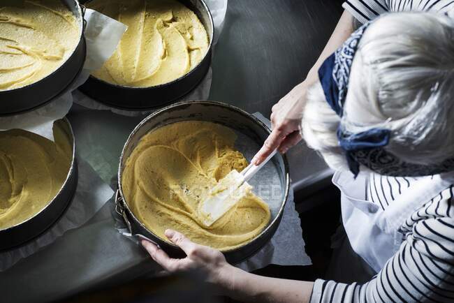 Pastella torta essere sparsi intorno a una tortiera con una spatola — Foto stock