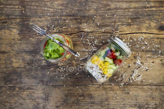 Салат из риса в стеклянной банке с диким рисом, сладкой кукурузой, огурцом, помидорами и салатом из баранины — стоковое фото