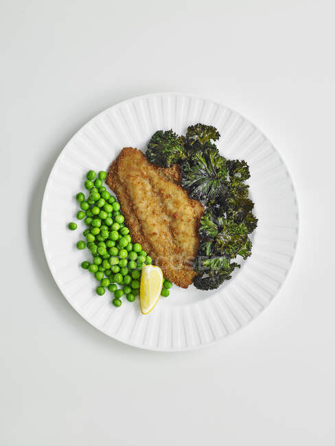 Fish schnitzel with kale chips and peas — Stock Photo