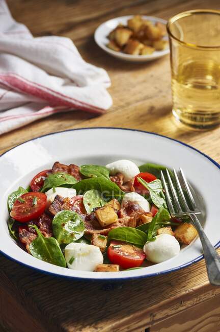 Salat mit Baby-Spinat, Tomate, Mozzarella, Kartoffelcroutons und Speck — Stockfoto