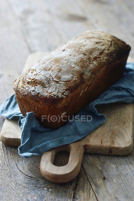 Wholemeal bread on cloth and wooden board — Stock Photo