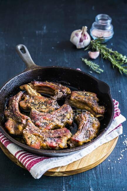 Pork ribs in a pan with garlic and fresh herbs — Stock Photo