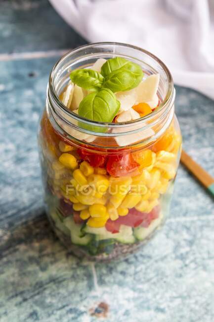 A colourful salad in a glass jar with red quinoa, cucumber, peppers, corn, tomatoes, pecorino and basil — Stock Photo