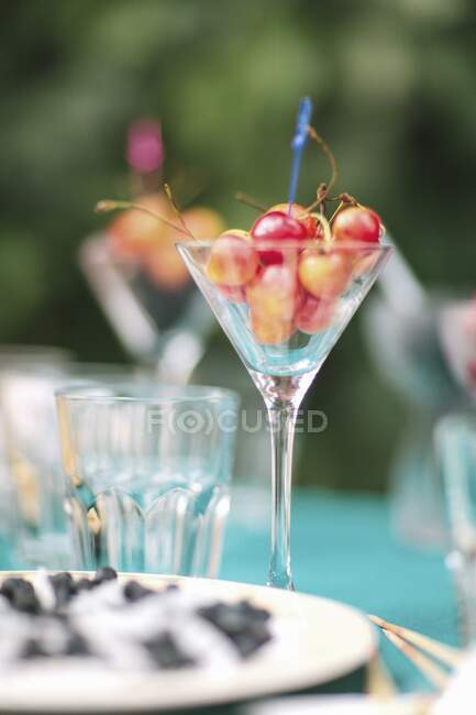 Стакан вишни на садовом столе — стоковое фото