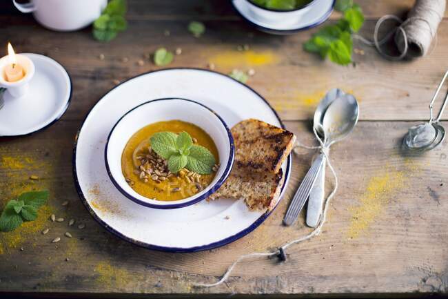 Pumpkin Carrot Soup decorated with fresh mint leaves and sunflower seeds — Stock Photo