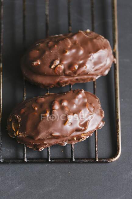 Biscuits aux noix recouverts de chocolat sur un support de refroidissement métallique — Photo de stock
