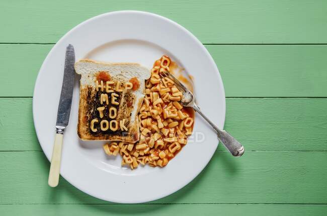 Burnt toast with the lettering help me to cook in pasta shapes — Stock Photo