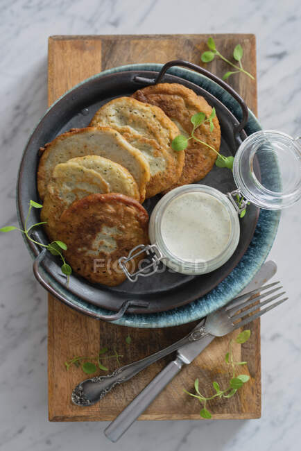 Batatas e panquecas de abobrinha com molho de iogurte em jarra — Fotografia de Stock