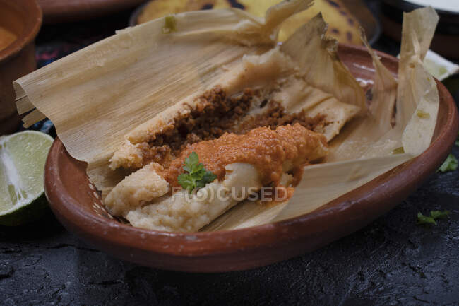 Vegan tamales filled with seitan, masa, chile verde and served with ranchero sauce, cream and chili beans — Stock Photo