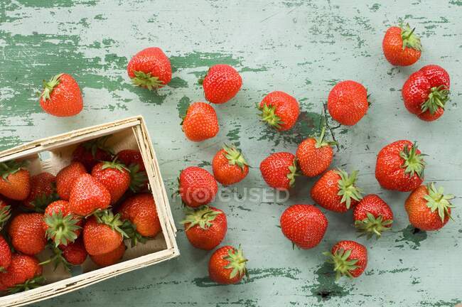 Fresh strawberries in wooden crate and on wooden table — Stock Photo