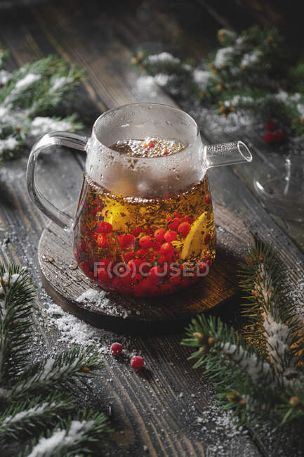 Preparazione di tè nero con bacche di viburno e limone con rami di abete e neve — Foto stock