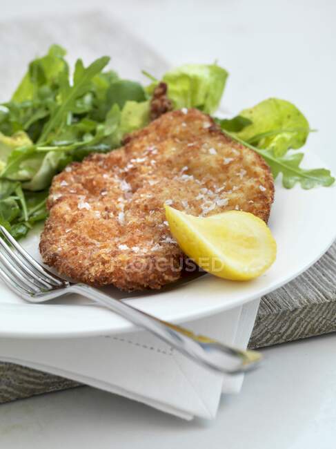 Milanese chicken slices with rocket salad and lemon — Stock Photo