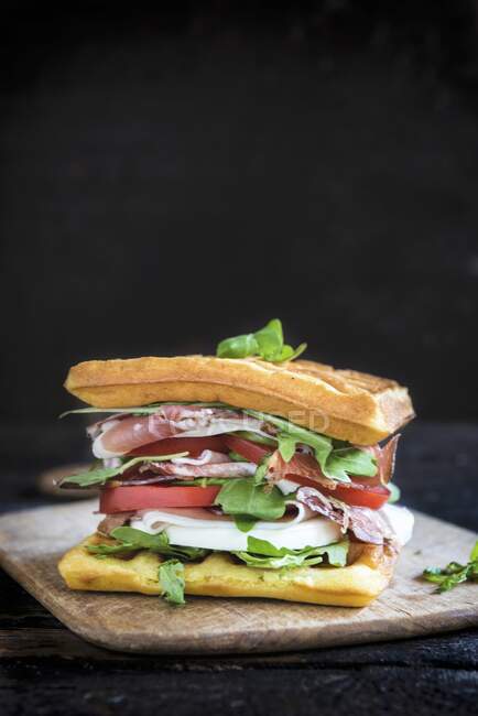 A waffle sandwich with ham, tomato, mozzarella and rocket — Stock Photo