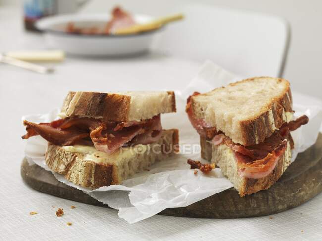 Sandwich con queso y tocino crujiente, cortado en dos partes - foto de stock