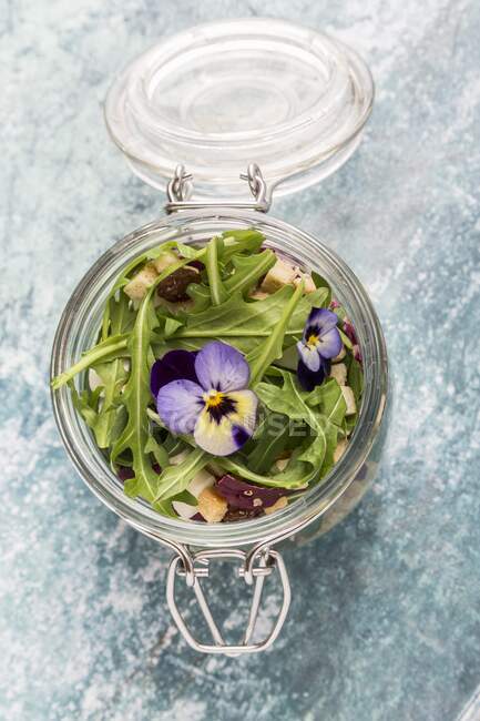 Quinoa salad with lambs lettuce, radicchio, rocket, croutons, goat's cheese and horned violets in a glass jar — Stock Photo