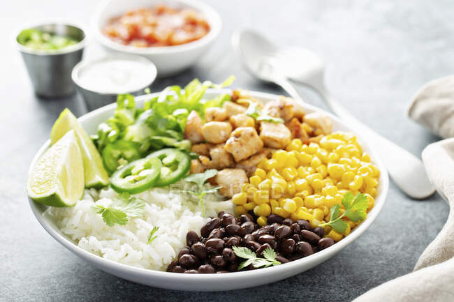 Gebratene Hühnerkeulen mit Reis, Bohnen, Mais, Limetten und Kräutern — Stockfoto