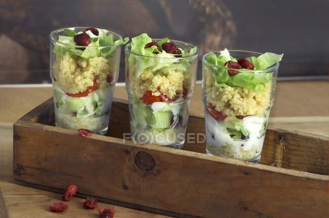 Couscous salad with tomatoes, iceberg lettuce and cranberries in glasses — Stock Photo