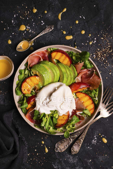 Salat mit Rucola, Pfirsichen, Avocado, Burrata und Parmaschinken — Stockfoto