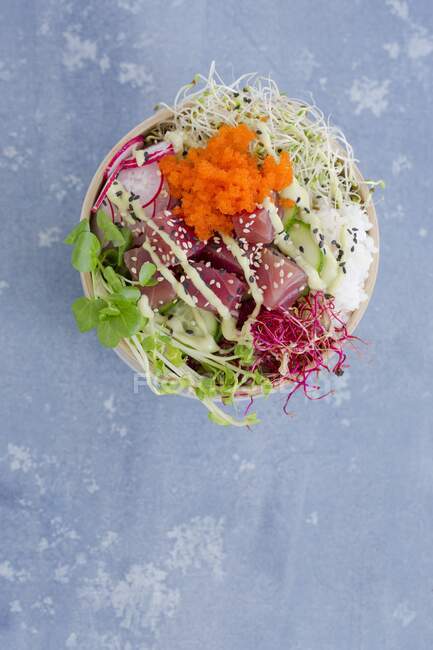 Poke bowl with tuna, sushi rice, tobiko, radishes, cucumber slices, and sprouts — Stock Photo