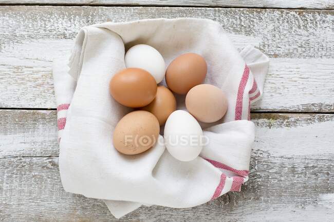 Huevos de pollo en toalla de té sobre fondo de madera - foto de stock