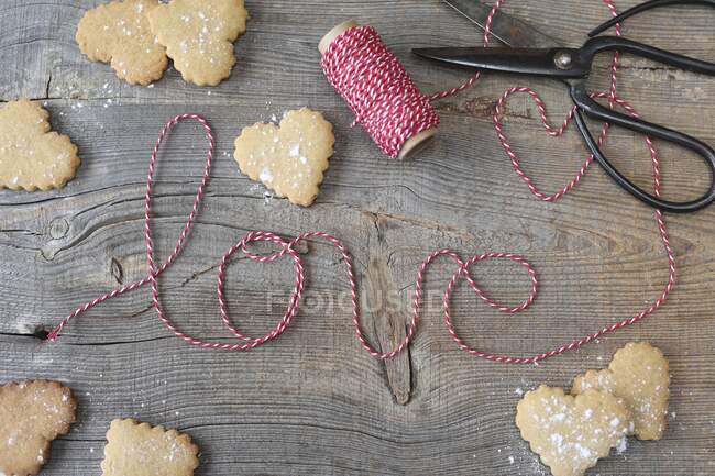 Biscoitos em forma de coração e cordas listradas soletrando a palavra 'amor' — Fotografia de Stock