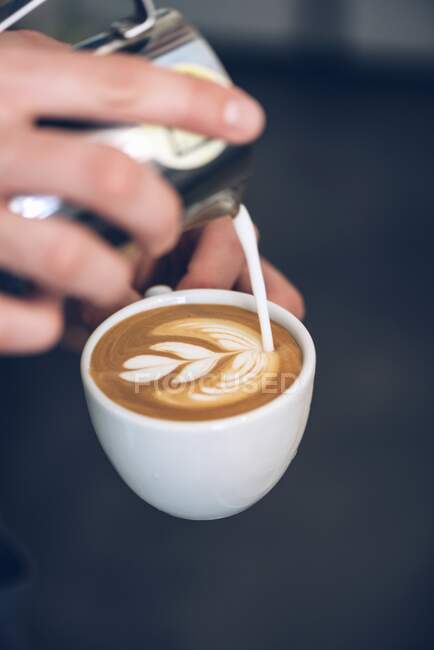 Un barista haciendo arte latte - foto de stock