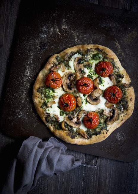A vegetarian pizza with tomatoes, mushrooms, pesto and mozzarella — Stock Photo