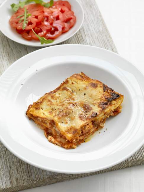 A portion of lasagne with a tomato salad — Stock Photo