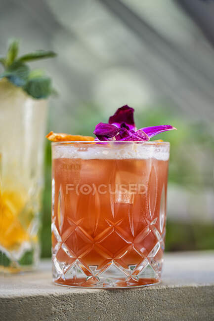 Розовый коктейль в стакане, украшенный цветком орхидеи — стоковое фото