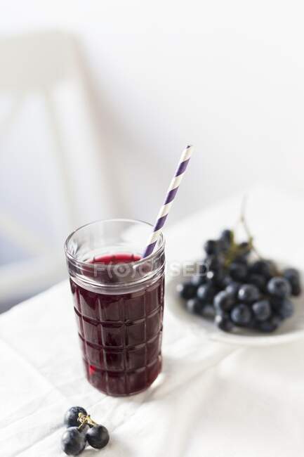 Red grape juice in glass with straw — Stock Photo